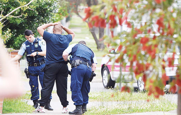 Police pull over and search a man and his vehicle near a house which was raided earlier Wednesday morning on Bursill Street at Guildford in Sydney’s west, on Oct 7. (Inset): Women walk past a home where police are conducting a search in the suburb of Guildford in Sydney on Wednesday. (AP)