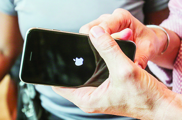 In this file photo, a customer tries out his Apple iPhone 6s smartphone at the Apple store at The Grove in Los Angeles. Apple reports quarterly financial results on Oct 27. (AP)