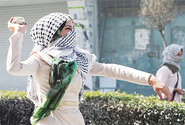 A Palestinian student from Hebron University throws a stone towards Israeli soldiers and border police during clashes after the Palestinian protesters blocked the main north entrance of the West Bank town of Hebron with stones and tyres
