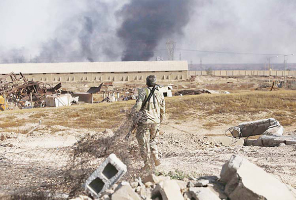 An Iraqi Shiite fighter from the Popular Mobilisation units, fighting alongside Iraqi forces, walks in the town of Baiji north of Tikrit, during fighting against the Islamic State (IS) jihadist group to retake the strategic northern Iraqi town