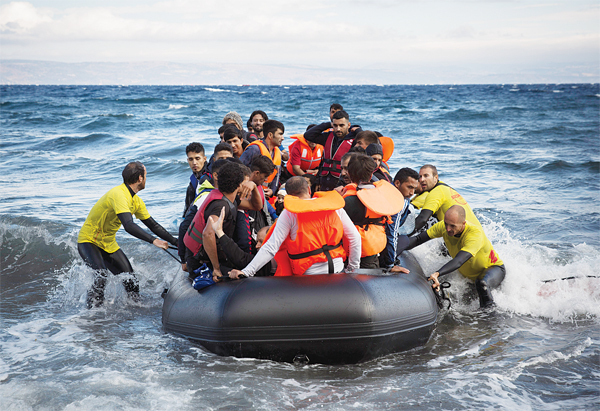 Four lifeguards from Barcelona, Spain, working as volunteers, help disembarking a dinghy as migrants and refugees arrive from the Turkish coasts to the northeastern Greek island of Lesbos