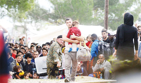 A man holds his child as migrants and refugees move past Macedonian police while attempting to enter into Macedonia at the Greece-Macedonia border near the town of Gevgelija