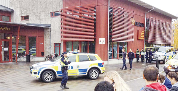Swedish police officers secure the area outside a primary and middle school in Trollhattan, southwestern Sweden, on Oct 22, where a masked man armed with a sword injured an adult and four students before being arrested by police. (AFP)