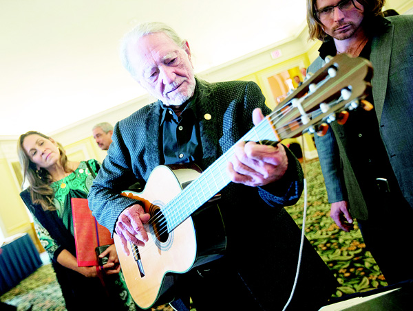 Musician Willie Nelson plays a guitar that was donated to the Library of Congress by Burl Ives, during a tour of items from Musical Division at the Library of Congress in Washington, Nov 17. Nelson is being honored as the new recipient of the Library of Congress Gershwin Prize for Popular Song and with him are his wife Annie D’Angelo (left), and son Lukas Nelson (right). (AP)