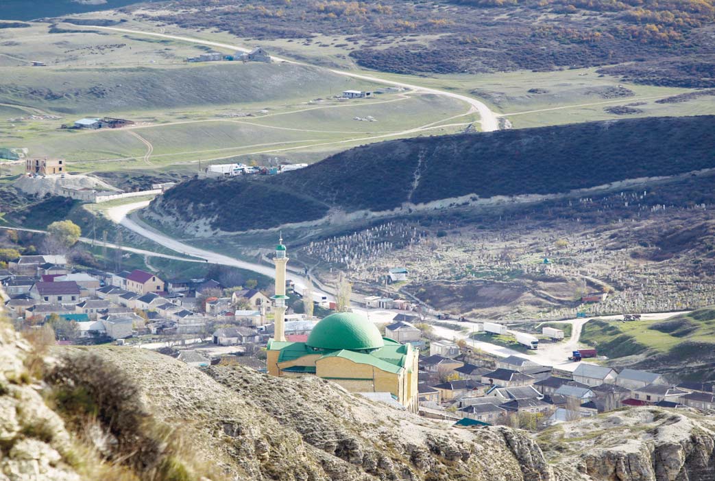 In this photo taken on `Nov 12, a mosque is seen from the mountains in the village of Gubden, Dagestan, Russia. An epidemic of recruitment for the Islamic State group has swept through the predominantly Muslim Dagestan where young men and women are leaving for Syria, pursuing a religious ideal or trying to escape police profiling. (Inset): In this photo taken on Nov 12, Abdulla Magomedov, brother of Rashid Magomedov who left to become an Islamic State fighter and was killed in Syria, sits at home in the village of Komsomolskoye, Dagestan, Russia. (AP)