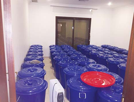 A large number of plastic barrels filled with local liquor are kept in a room to cook at certain temperature