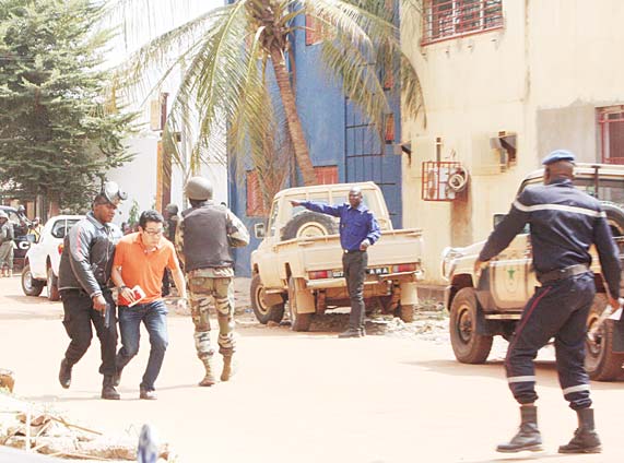 A Mali trooper (left), assists a hostage (second left), to leave the scene, from the Radisson Blu Hotel to safety after gunmen attacked the hotel in Bamako, Mali on Nov 20. (AP)