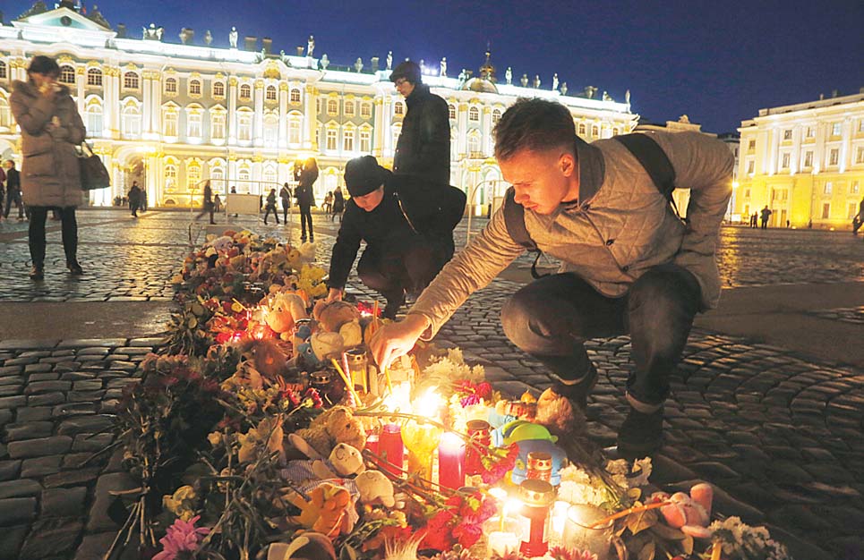 A man lights a candle in memory of the plane crash victims at Dvortsovaya (Palace) Square in St Petersburg, Russia on Nov 3. Mourners continue to come to St Petersburg’s Pulkovo Airport and Dvortsovaya Square on Tuesday to lay flowers and leave paper planes and soft toys at the arrivals hall. (AP)