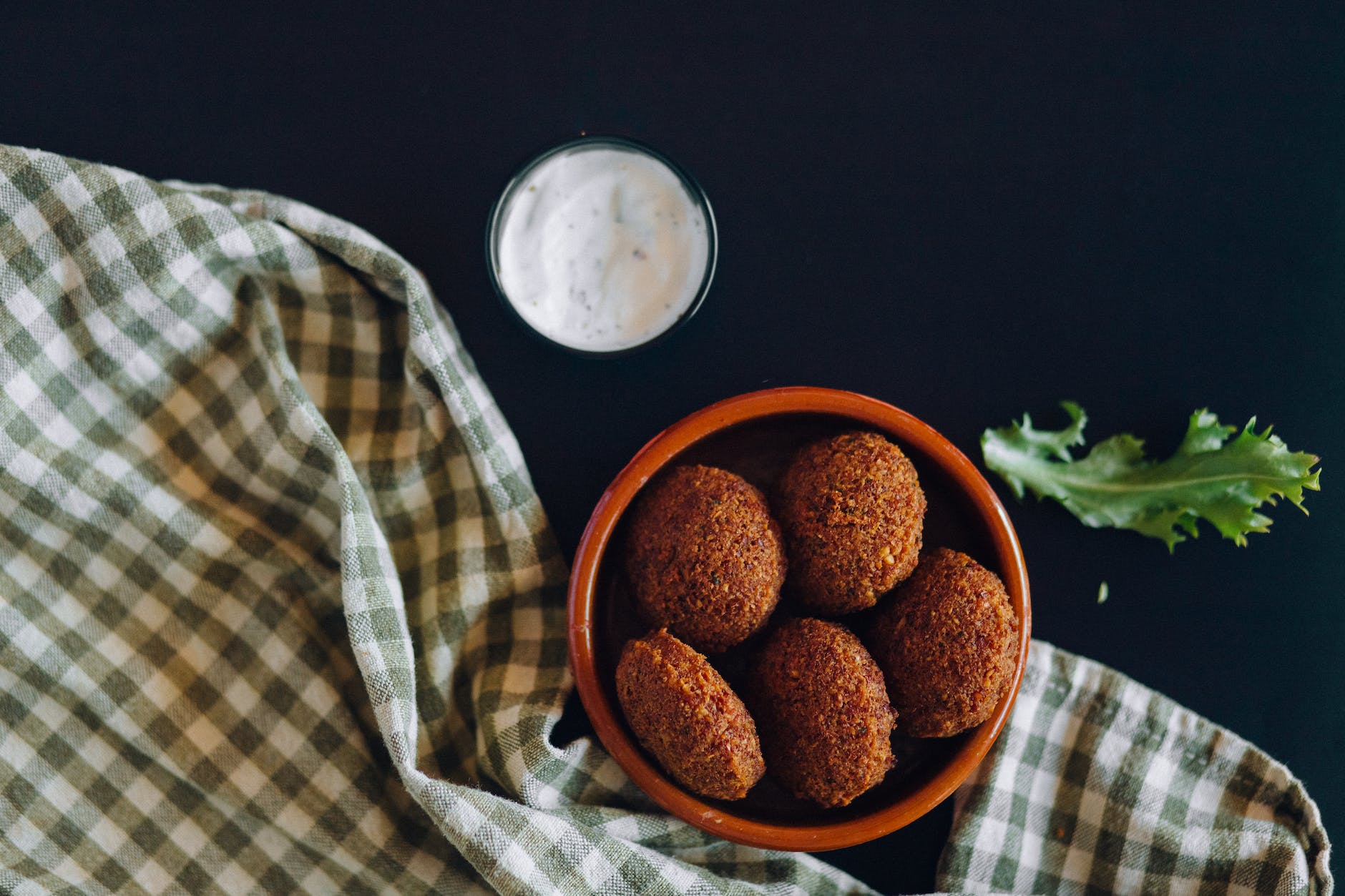 photo of a bowl of falafels near a white dipping sauce
