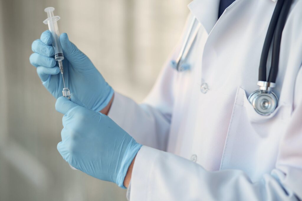 person in white long sleeve shirt holding injection